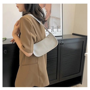 Minimalist white faux leather baguette bag shown as a stylish shoulder bag on a model