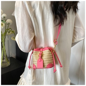 Detailed back view of model wearing a pink straw patchwork bucket bag with crossbody strap