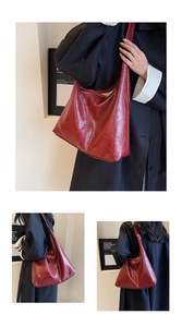 Macro detail of deep red leather tote bag showing glossy texture and spacious design
