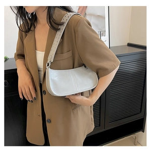 Detail of light grey underarm bag featuring metal eyelet strap and silver hardware