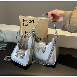 Detail showing two silver metallic bow handbags in large and small sizes with chain straps