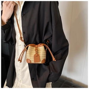 Detail of mini straw bucket bag with brown leather trim and drawstring closure