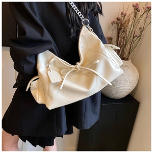 Detail der cremeweißen PU-Leder Schultertasche mit schicker Schleife und Silberkette