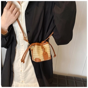 Mini straw bucket bag with brown leather trim and drawstring shown on a model