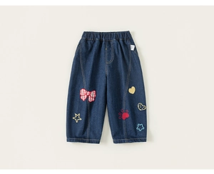 Détail du pantalon en jean pour filles avec nœuds brodés et écussons d'étoiles sur denim