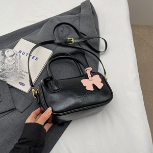 Chic black PU leather barrel handbag with gold hardware and pink bow charm for women