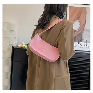 Detail of pink pebbled leather shoulder bag featuring dense silver stud decorations on strap