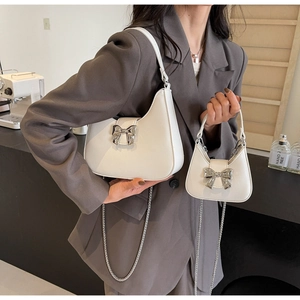 Detail of two-piece white hobo bag set with silver bow buckle and metal chain strap