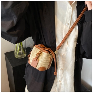 French style straw bucket bag with brown leather trim and slim shoulder strap