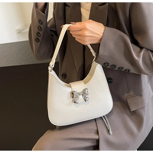Close-up of white lychee leather hobo bag with silver bow detail and delicate chain