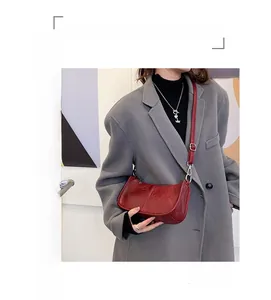 Close-up of the red polished leather texture and adjustable strap of the crescent bag