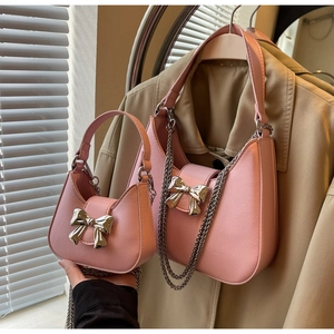 Detailed view of pink leather half-moon bags with silver bow metal charms and chain straps