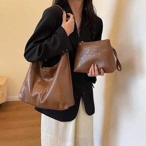 Vintage brown leather tote bag with matching pouch shown on a stylish fashion model