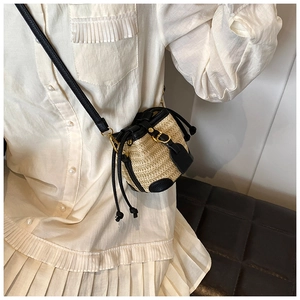 Detail view of the straw bucket bag showing black leather trim and drawstring on a model