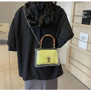 Detail of transparent PVC crossbody bag with yellow woven liner and bamboo handle