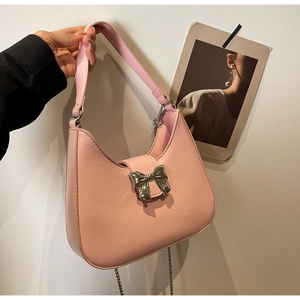 Detail of pink PU leather handbag featuring a polished silver metal bow buckle and texture