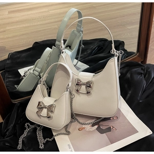 Detail showing two sizes of cream PU leather bow bags with silver chain straps and bows