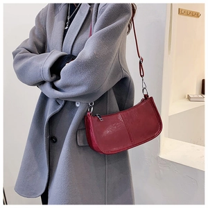 Close-up of a stylish burgundy crossbody bag with silver buckle and crocodile texture