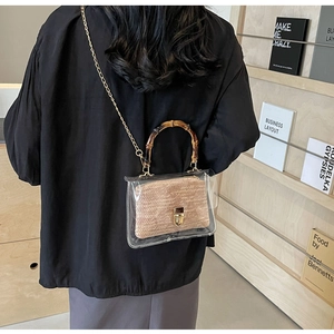 Detail view of transparent PVC crossbody bag featuring bamboo handle and woven straw insert
