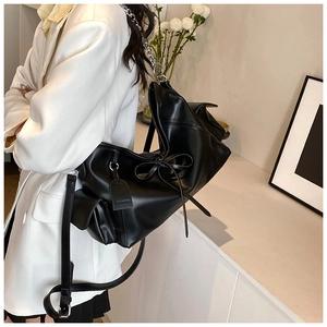 Detail einer schwarzen PU-Ledertasche mit Schleife und stylischem silbernem Ketten-Griff