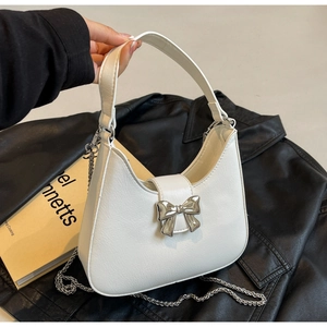 Detail of white saddle bag with silver bow buckle, leather handle and metal chain strap