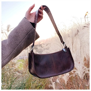 Detail of vintage brown moon-shaped shoulder bag with silver rivet-studded strap detail