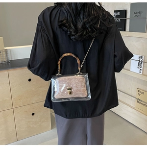 Detail of transparent PVC crossbody bag featuring a bamboo handle and inner fabric pouch