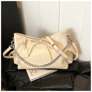 Cremefarbene PU-Leder Tote Tasche mit Silberkette und Schleife auf schickem Hintergrund