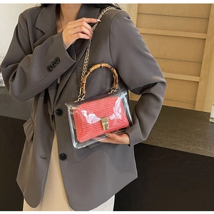 Detail of transparent PVC handbag featuring a retro bamboo handle and red woven inner pouch