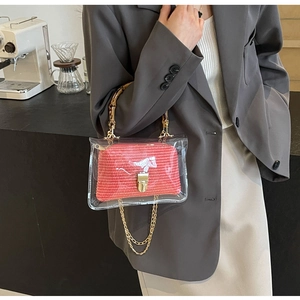 Fashionable PVC crossbody bag with red straw lining and bamboo handle in a cafe setting