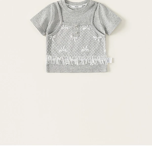 Dettaglio di una t-shirt grigia per bambini con pizzo e fiocchi ricamati carini
