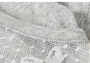 Dettaglio ravvicinato di morbida maglia grigia con bordo in pizzo a rete bianca