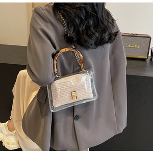 Detail of transparent PVC handbag featuring bamboo handle and golden metal lock
