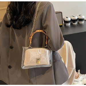 Detail of transparent PVC crossbody bag with bamboo handle and beige inner pouch on model