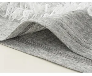 Dettaglio ravvicinato della maglia in cotone grigio e orlo in pizzo bianco a strati