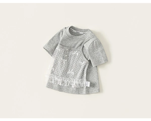 Dettaglio di una maglietta grigia per bambini con pizzo bianco, fiocco e pois