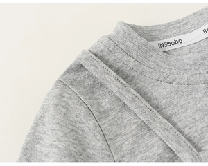 Dettaglio della cucitura del collo e del tessuto in cotone grigio per bambine