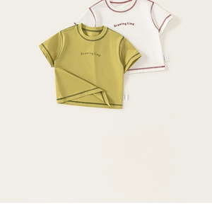 Dettaglio di t-shirt per bambini giallo senape e bianco con stampa e cuciture a contrasto