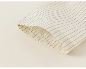 Close-up of blue striped sleeve cuff on cream toddler shirt with neat stitching detail
