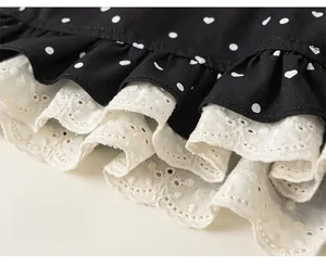 Detailed macro view of girls' black polka dot shorts with white lace eyelet embroidery