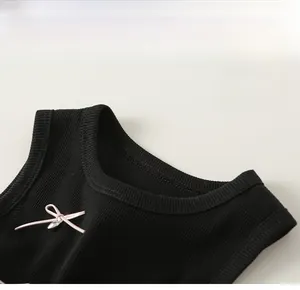 Close-up of black ribbed knit dress with classic round neck and pink bow detail