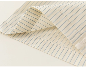 Detail of blue and white striped shirt fabric with white zipper and fine stitching