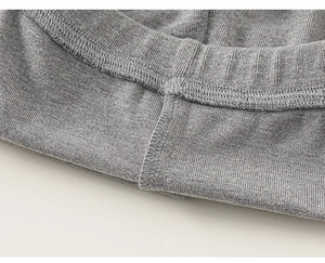 Detailopname van grijze gebreide stof met elastische tailleband en fijne stikseldetails