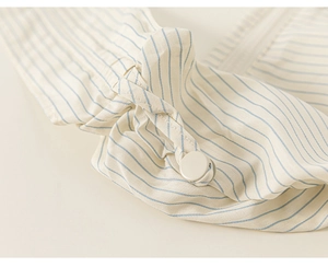 Detailed close-up of striped shirt cuff with button and strap on lightweight cotton fabric