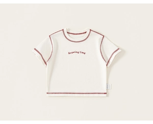 Dettaglio della t-shirt per bambini crema con cuciture rosse e stampa testo Growing time