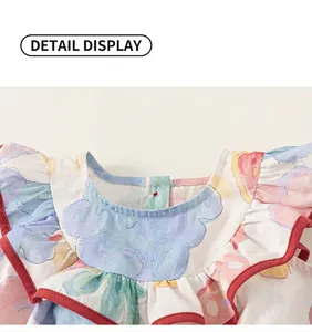 Detail eines Baby-Baumwollkleides mit Rundhalsausschnitt und Rüschen mit roter Paspelierung