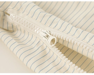 Detailed macro view of white resin zipper on light blue striped cotton fabric for girls
