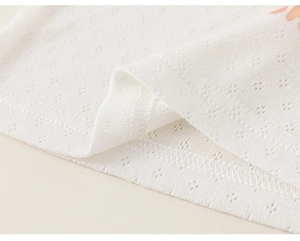 Close-up of white pointelle knit fabric showing breathable diamond pattern and fine stitching