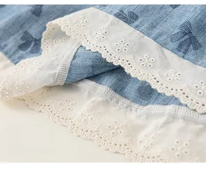 Detail showing tiered white lace embroidery and blue bow patterns on soft cotton fabric
