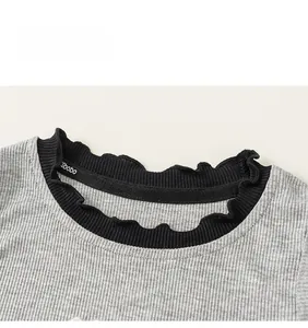Close-up of knit top neckline with black ribbing and delicate ruffle trim details